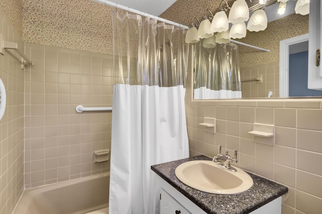 bathroom featuring tasteful backsplash, vanity, wallpapered walls, shower / bath combo with shower curtain, and tile walls