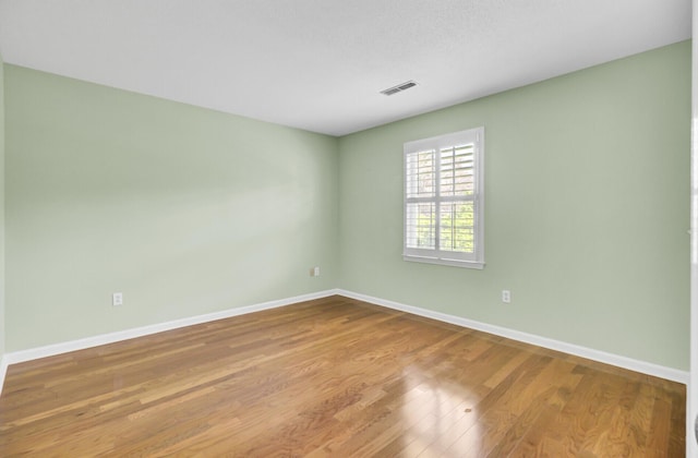 spare room featuring visible vents, baseboards, and wood finished floors