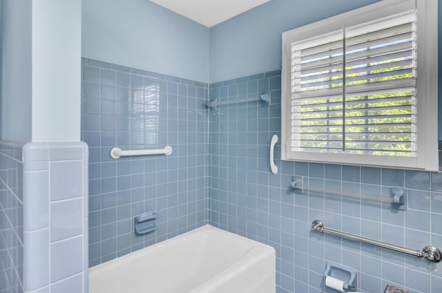 bathroom with shower / bath combination and tile walls
