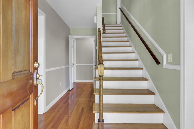 staircase featuring baseboards and wood finished floors