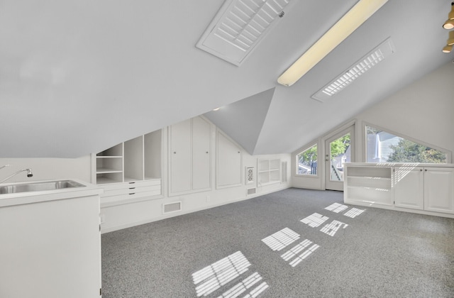 bonus room with visible vents, built in shelves, a sink, carpet floors, and vaulted ceiling