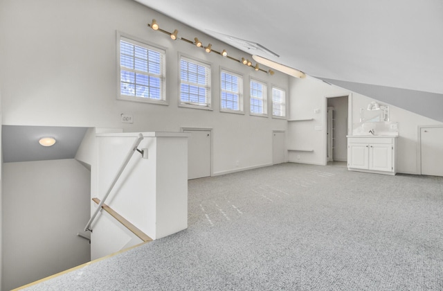 additional living space with light colored carpet and vaulted ceiling