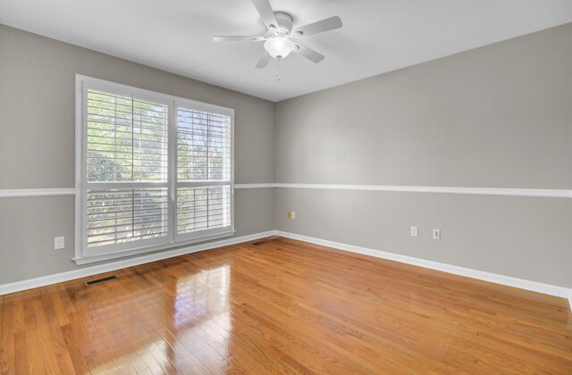 empty room featuring visible vents, baseboards, wood finished floors, and ceiling fan