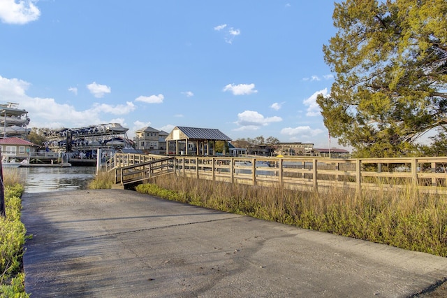 exterior space featuring a water view, fence, and a dock