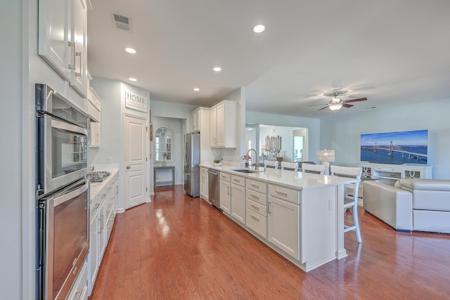 kitchen with sink, stainless steel appliances, white cabinets, and a kitchen bar