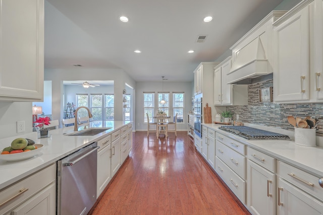 kitchen with decorative light fixtures, tasteful backsplash, sink, white cabinets, and stainless steel appliances