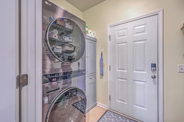 washroom featuring stacked washer and dryer, light tile patterned floors, and cabinets