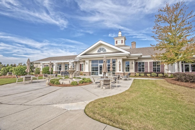 rear view of property featuring a patio and a lawn