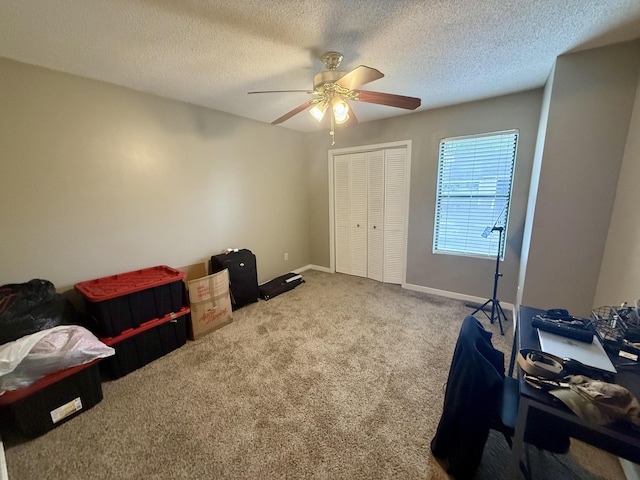 bedroom featuring ceiling fan, a textured ceiling, carpet floors, baseboards, and a closet