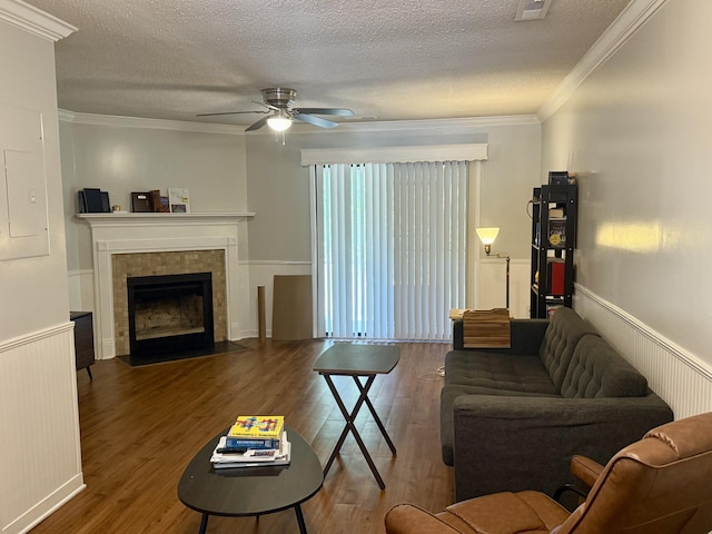 living area with a ceiling fan, a textured ceiling, ornamental molding, and wood finished floors