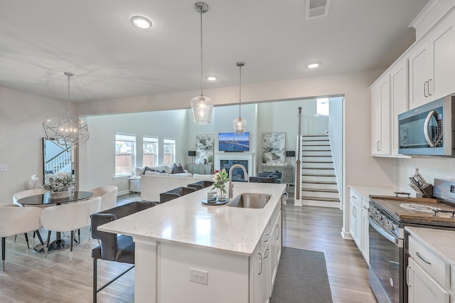 kitchen featuring visible vents, an island with sink, recessed lighting, a sink, and appliances with stainless steel finishes