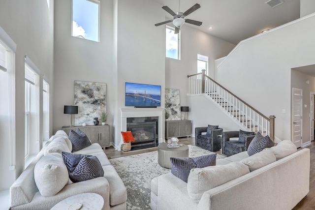 living area with wood finished floors, ceiling fan, a high ceiling, and a wealth of natural light