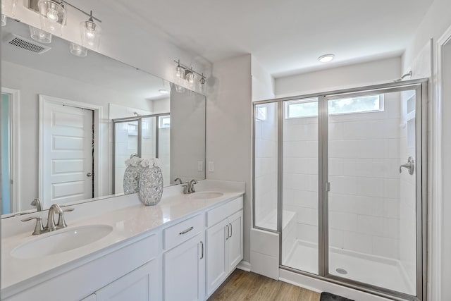bathroom with wood finished floors, visible vents, a sink, and a stall shower