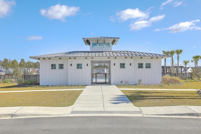 view of front of property featuring a standing seam roof, a gate, board and batten siding, and fence