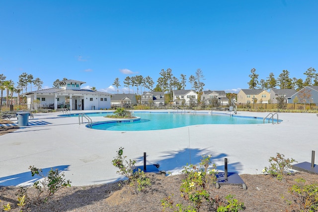 community pool with fence, a patio, and a residential view