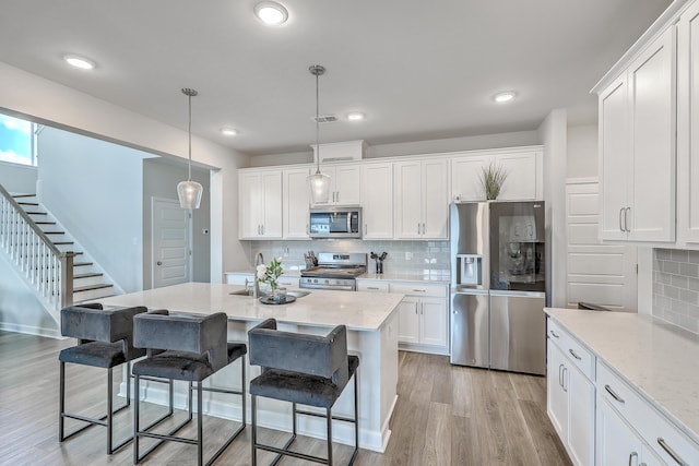 kitchen featuring a sink, appliances with stainless steel finishes, backsplash, and white cabinetry