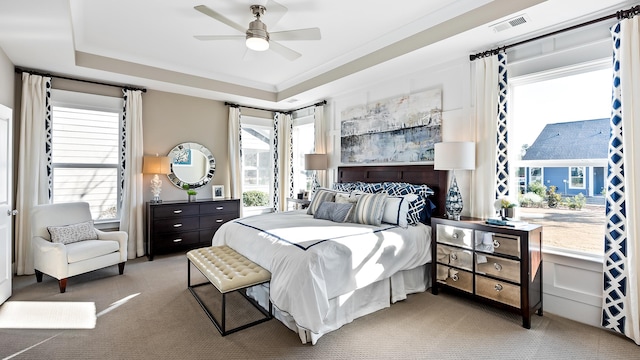 bedroom with multiple windows, ornamental molding, a raised ceiling, and carpet flooring