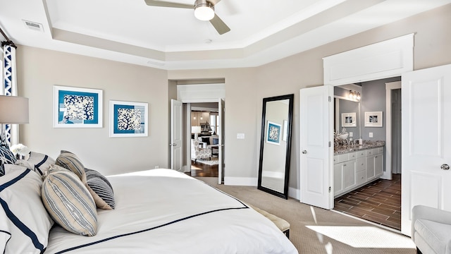 bedroom featuring ceiling fan, connected bathroom, and a raised ceiling