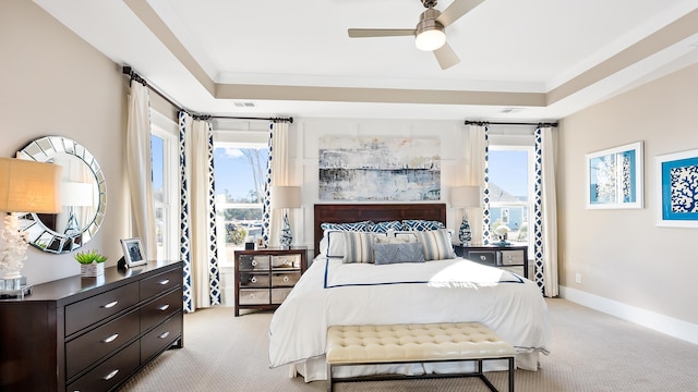 bedroom featuring ceiling fan, light colored carpet, a tray ceiling, and crown molding