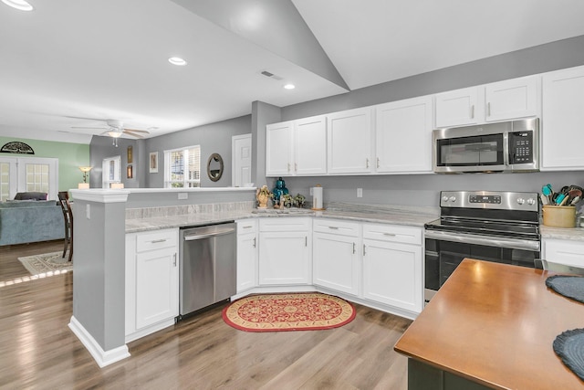 kitchen with appliances with stainless steel finishes, ceiling fan, white cabinets, and kitchen peninsula