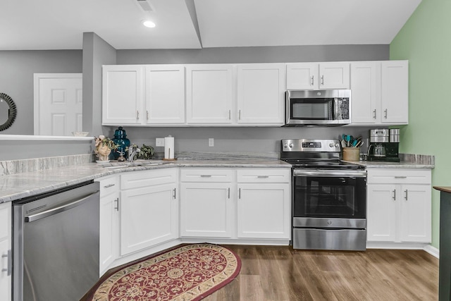 kitchen featuring light stone countertops, stainless steel appliances, hardwood / wood-style floors, white cabinetry, and sink