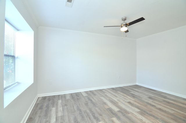 spare room with light wood finished floors, ornamental molding, visible vents, and baseboards