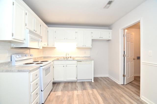 kitchen with white appliances, a sink, visible vents, white cabinets, and light countertops