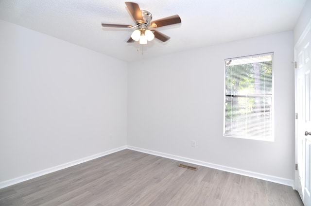 empty room featuring visible vents, ceiling fan, a textured ceiling, wood finished floors, and baseboards