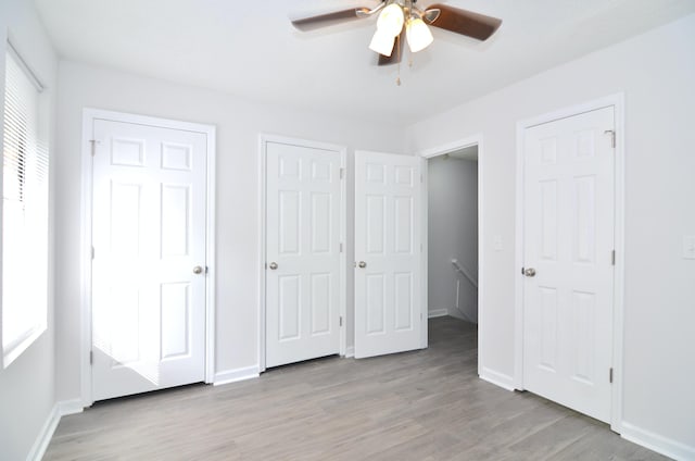 unfurnished bedroom with light wood-type flooring, multiple windows, and two closets