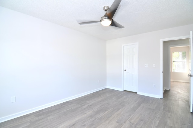 unfurnished bedroom featuring a closet, ceiling fan, wood-type flooring, and a textured ceiling