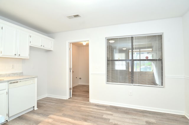 kitchen with white cabinets, light wood-style floors, white dishwasher, and light countertops