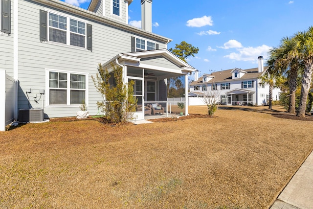 rear view of house with central AC unit, a yard, and a sunroom