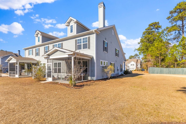 rear view of house featuring a yard and a sunroom