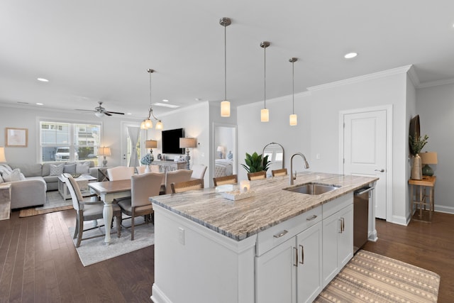 kitchen featuring ceiling fan, sink, an island with sink, white cabinets, and light stone counters