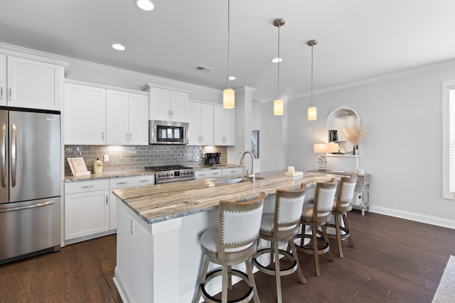 kitchen with sink, hanging light fixtures, a kitchen island with sink, stainless steel appliances, and white cabinets