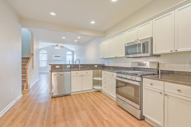 kitchen with stainless steel appliances, vaulted ceiling, kitchen peninsula, and light hardwood / wood-style flooring