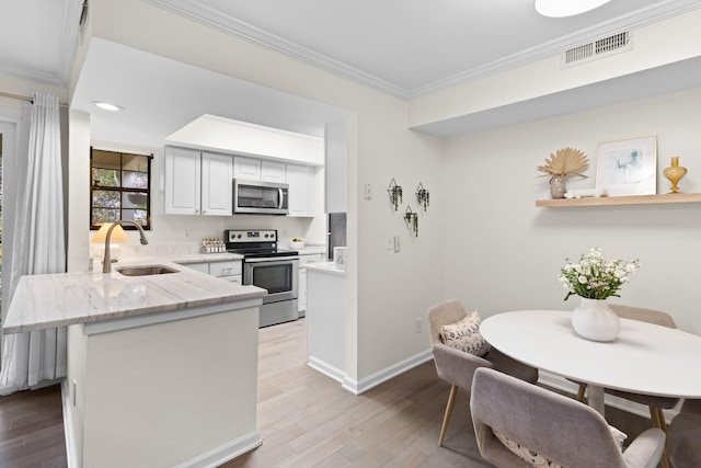 kitchen featuring sink, crown molding, light stone counters, appliances with stainless steel finishes, and light hardwood / wood-style floors