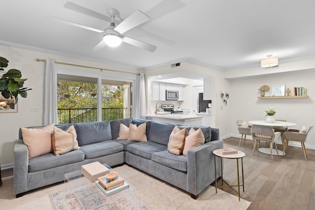 living room with ceiling fan, ornamental molding, sink, and light hardwood / wood-style flooring