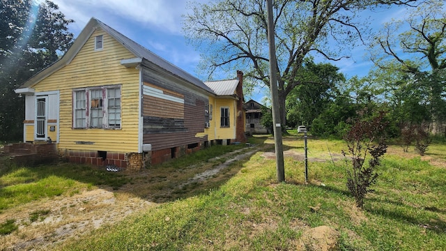 view of side of home with crawl space, a chimney, and metal roof