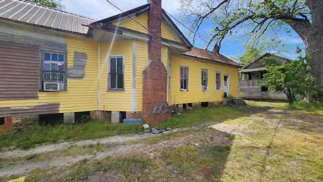 view of side of property with cooling unit, a chimney, and metal roof
