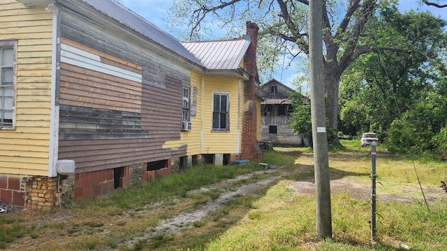 view of property exterior with a chimney and metal roof