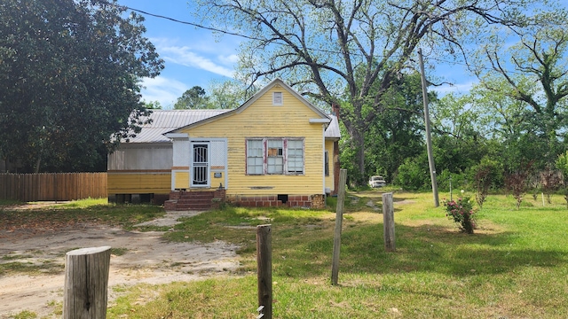 bungalow with crawl space, a front lawn, fence, entry steps, and metal roof