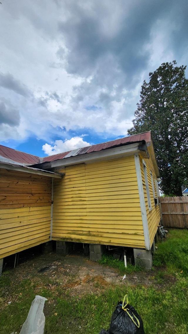 view of property exterior featuring metal roof and fence