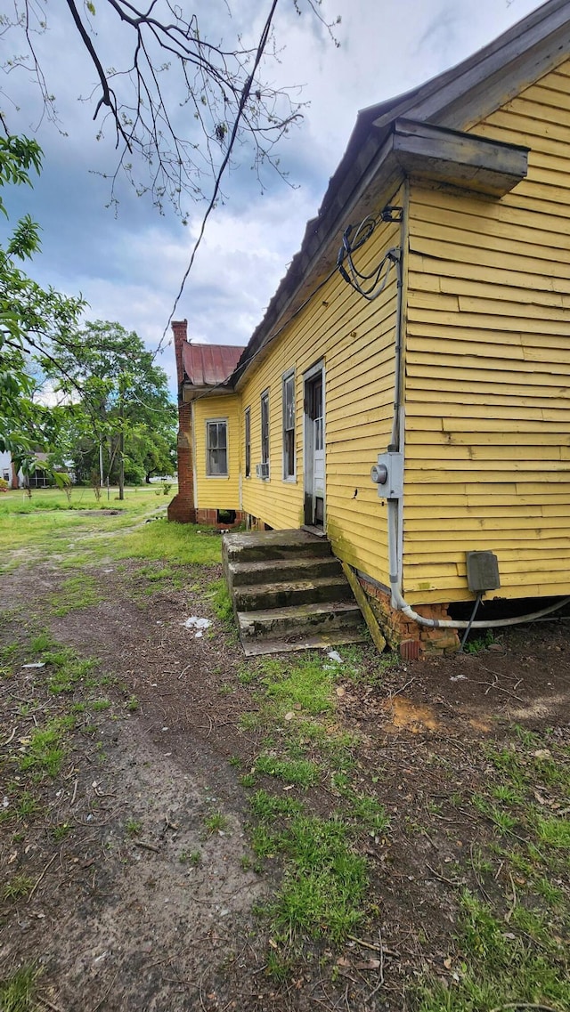 view of home's exterior with a chimney and entry steps