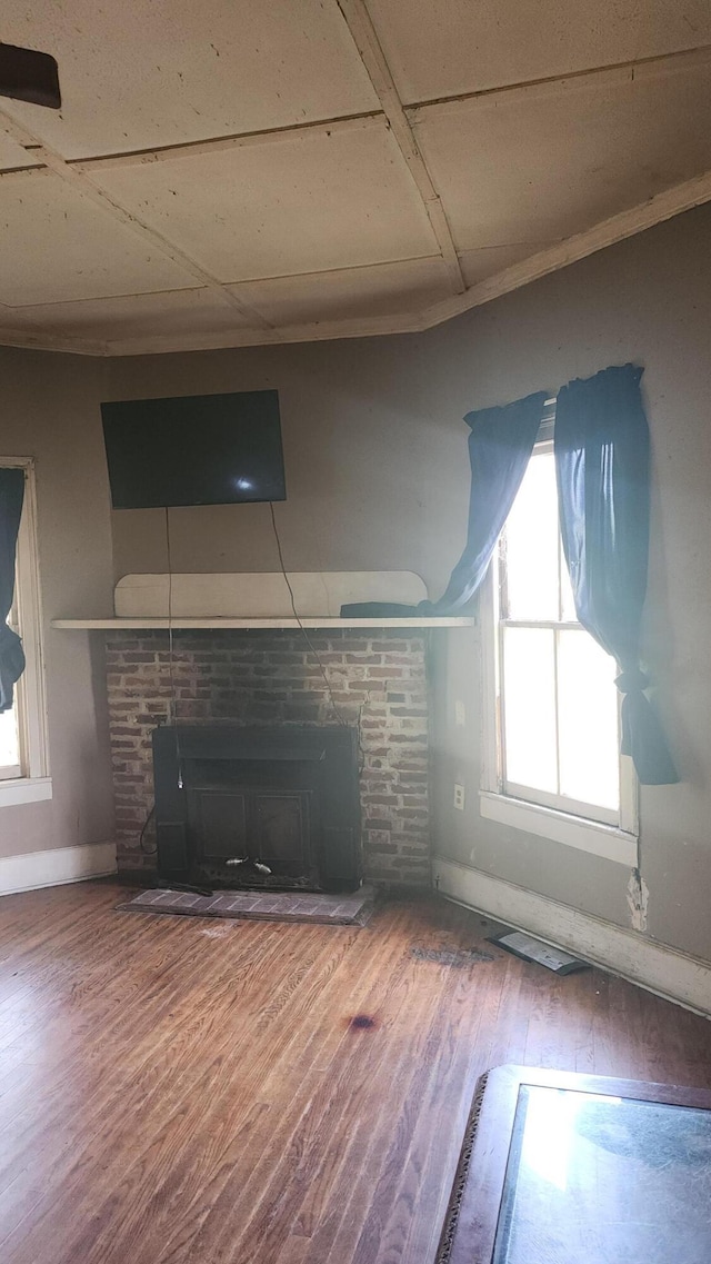 unfurnished living room featuring baseboards, a healthy amount of sunlight, wood finished floors, and a fireplace