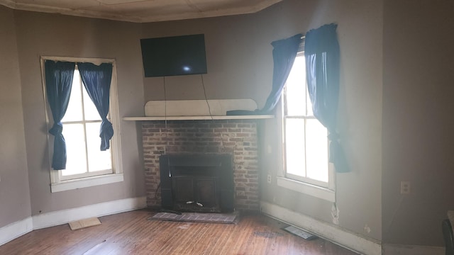 unfurnished living room featuring wood finished floors, visible vents, crown molding, baseboards, and a fireplace