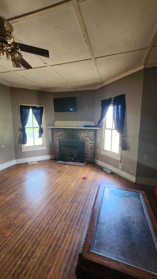 unfurnished living room featuring a fireplace, wood finished floors, a ceiling fan, and baseboards