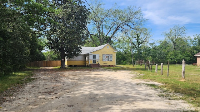 exterior space featuring metal roof, driveway, and fence