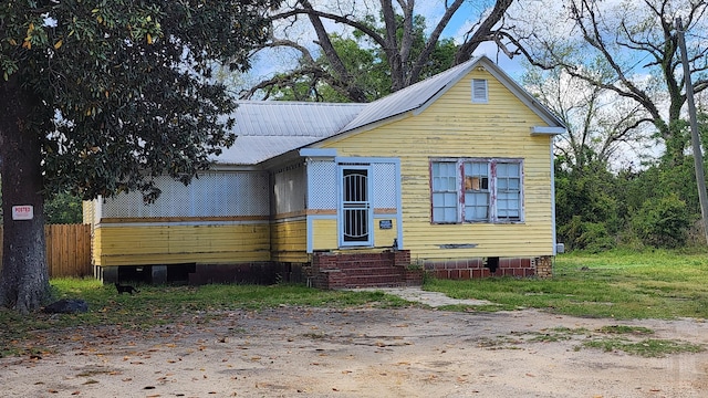 bungalow-style house with entry steps, crawl space, metal roof, and fence