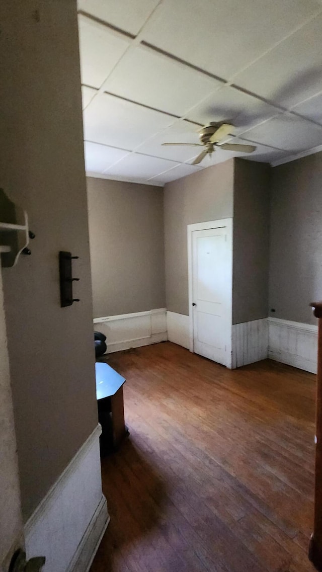 unfurnished room with wood finished floors, a wainscoted wall, and ceiling fan